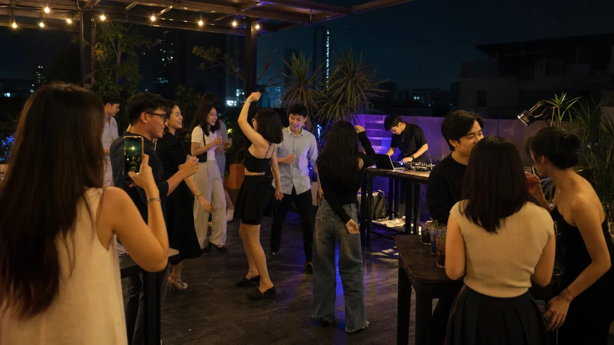Nhóm nhân sự trẻ người Việt tham gia tiệc cuối năm có âm nhạc và điện thoại quay video.